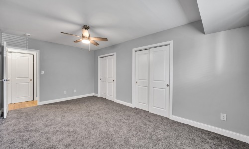 a bedroom with carpet and a fan